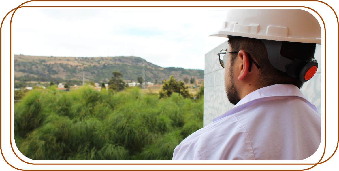 Ingeniero con casco y bata mirando hacia el horizonte