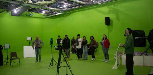 Los profesores Luis Antonio Sepúlveda y Luis Enrique Albesiano acompañan un taller en el estudio de televisión y muestran a los visitantes elementos de la producción audiovisual.