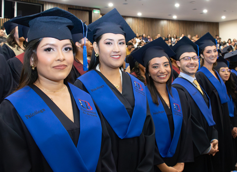 Grupo de egresados universitarios con toga y birrete durante ceremonia de graduación